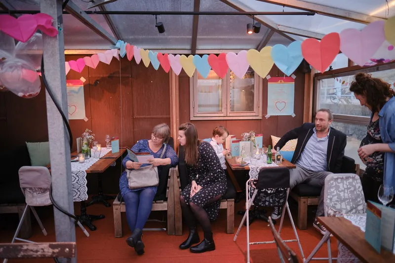Gasten aan lange tafels onder de vlaggetjes tijdens het diner