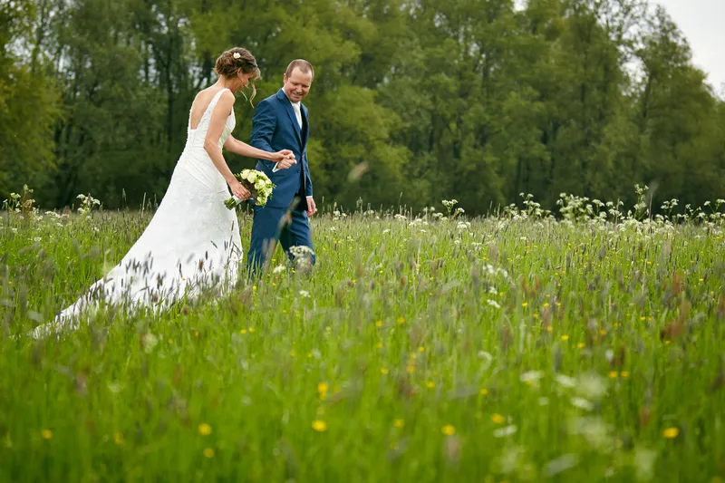 Elise en Maarten lopen door het hoge gras vol bloemen