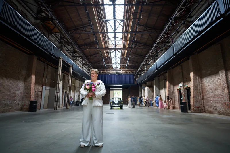 Froukje in haar witte pak wacht alleen in de lange hal