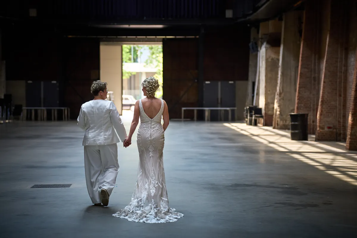 Froukje en Mireille lopen hand in hand naar de open deur aan het eind van de hal