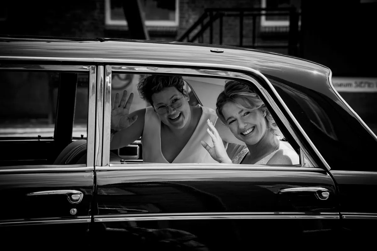 Froukje en Mireille lachen samen door het raam van de oldtimer, zwart-wit