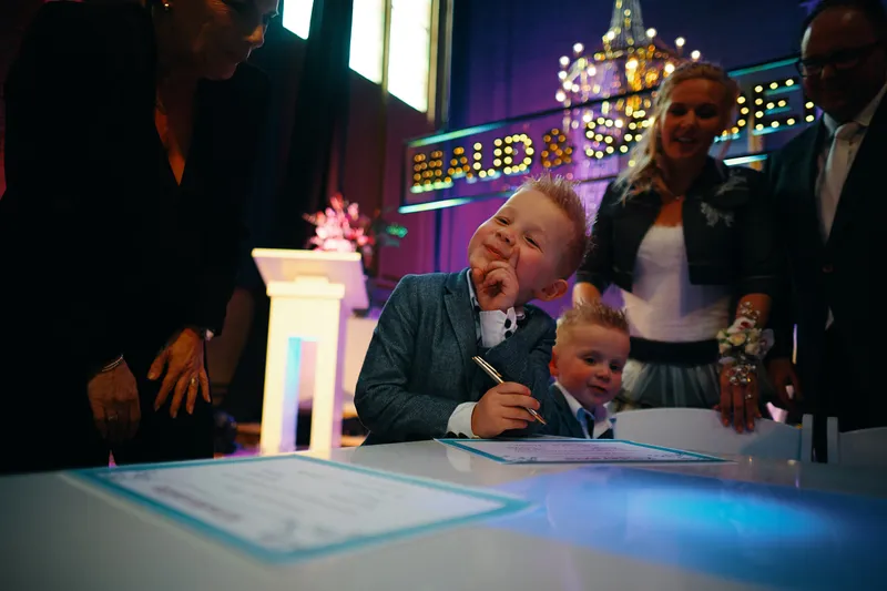 Een van hun zoons tekent mee aan de verlichte tafel