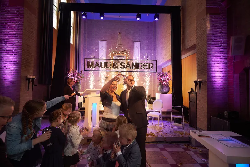 Maud en Sander voor het podium met hun namen in licht