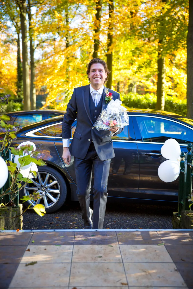 Martijn stapt uit de Jaguar, tussen het herfstblad