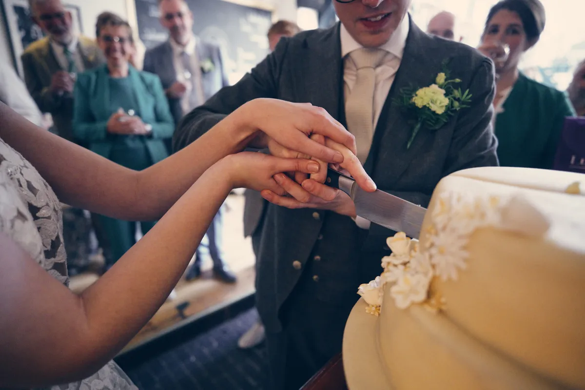 Yvo en Marjolijn snijden de taart aan, de gasten kijken toe