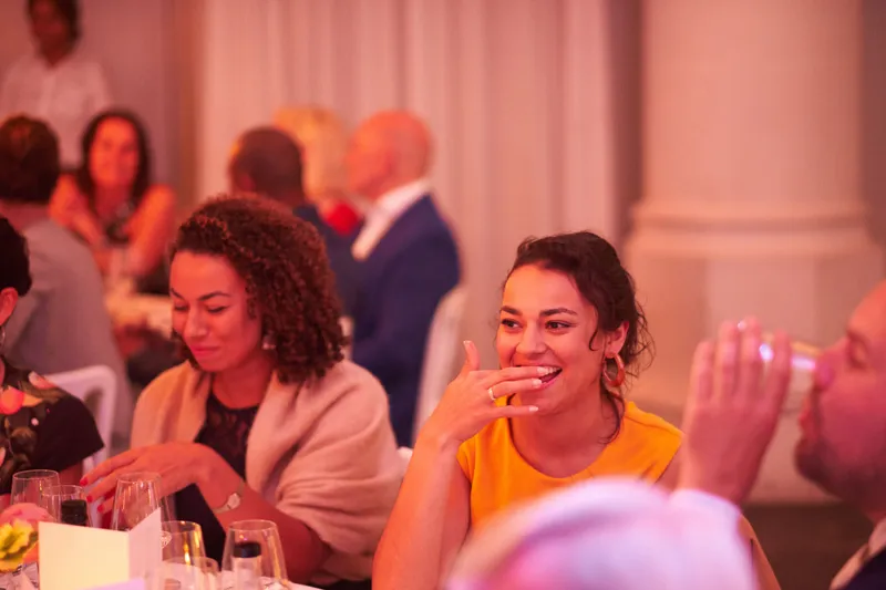 Gasten lachen om een speech tijdens het diner