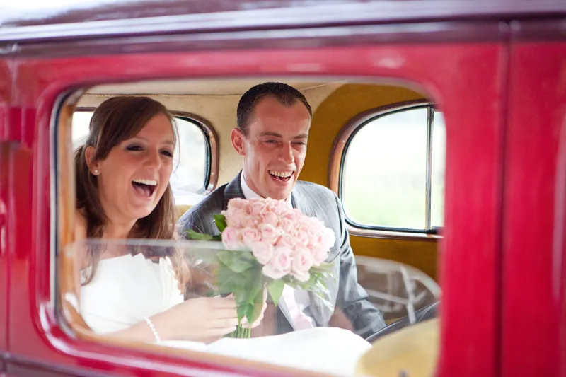 Jorinda en Gerben lachen in de rode oldtimer