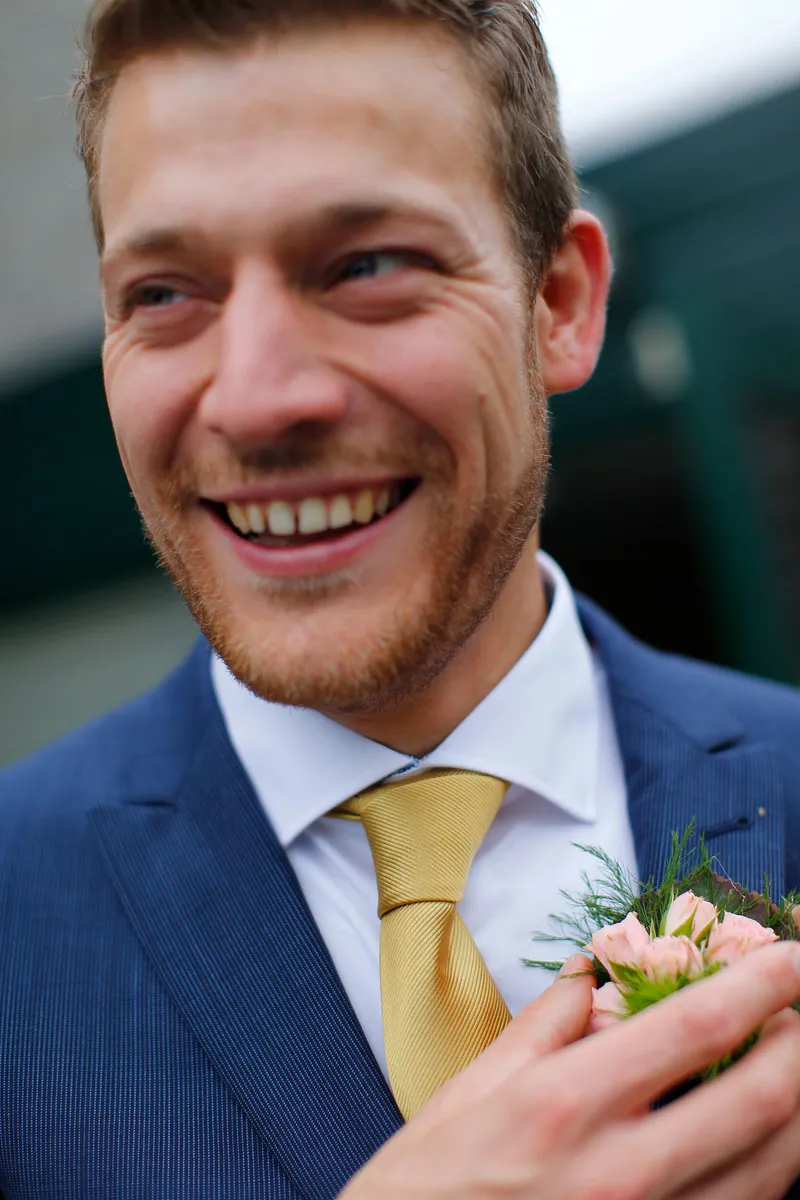 Een gast lacht met zijn corsage
