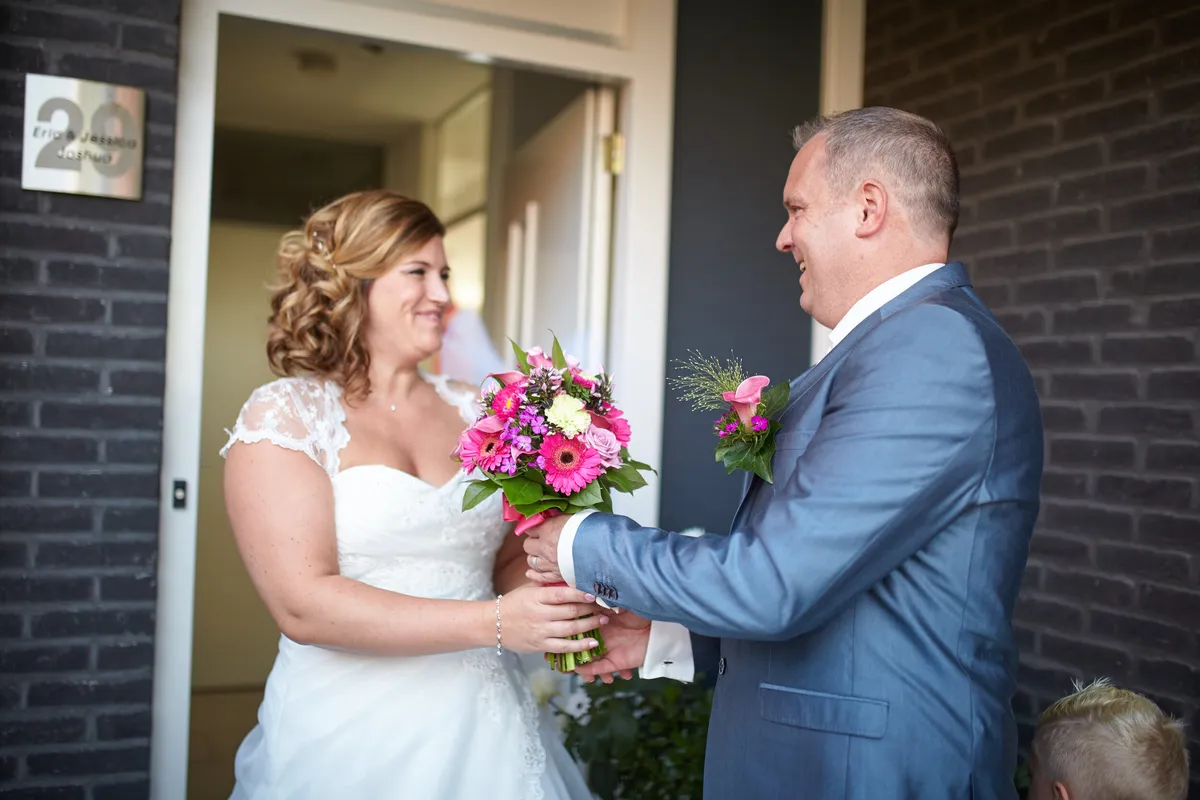 Eric en Jessica kijken elkaar aan voor de deur, het boeket tussen hen in