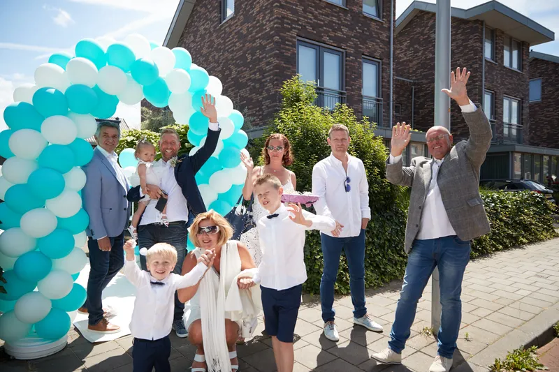 Familie en vrienden zwaaien onder de ballonnenboog