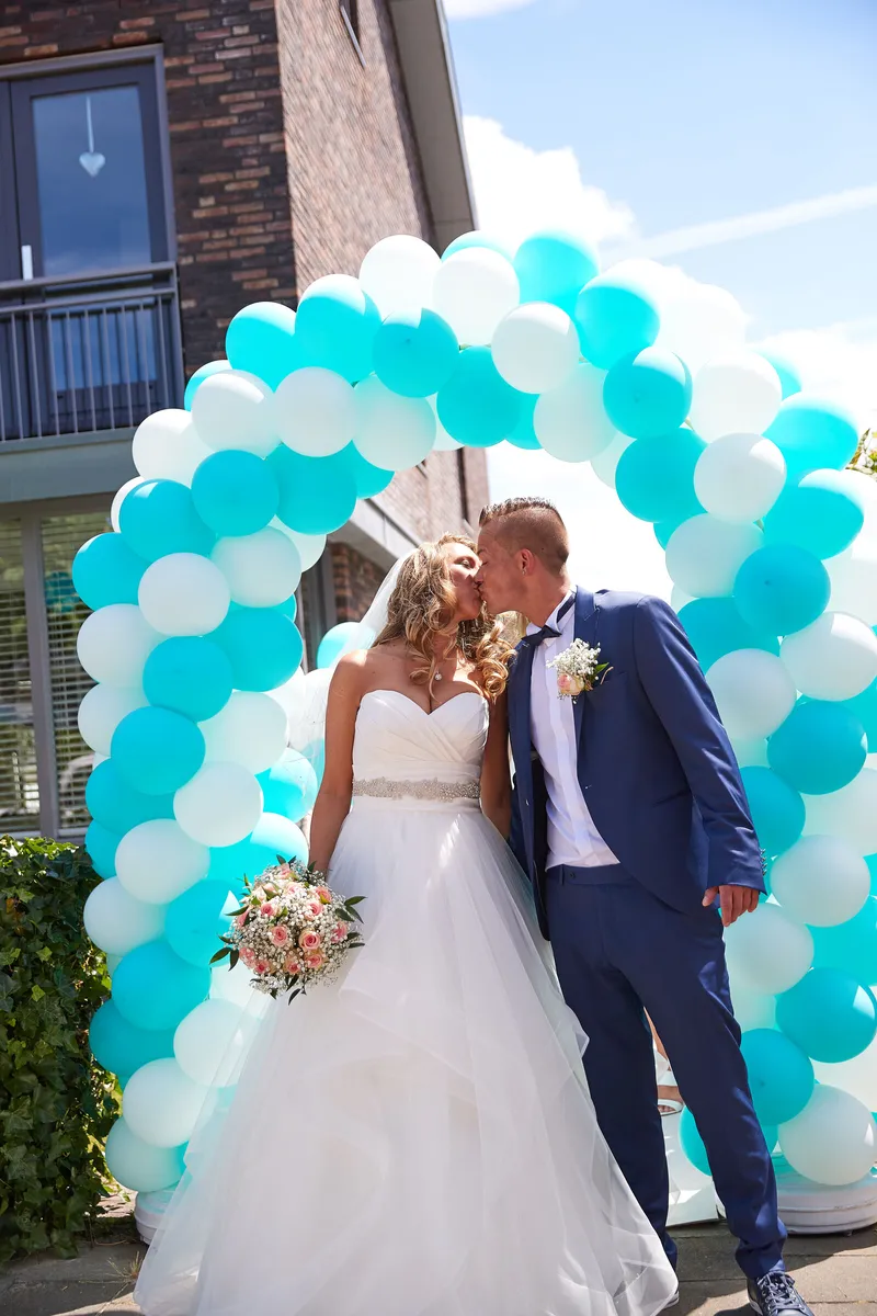 Bojaura en Jeffrey kussen onder de ballonnenboog