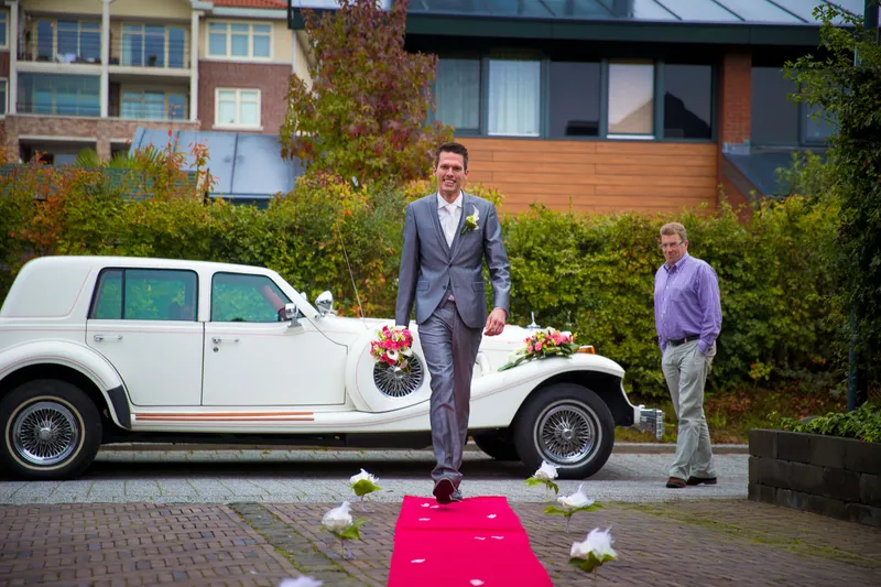 Mark loopt over de rode loper naar het huis, de witte oldtimer erachter