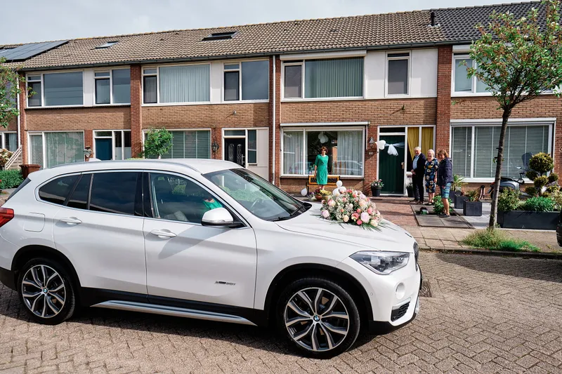 De witte trouwauto in de straat