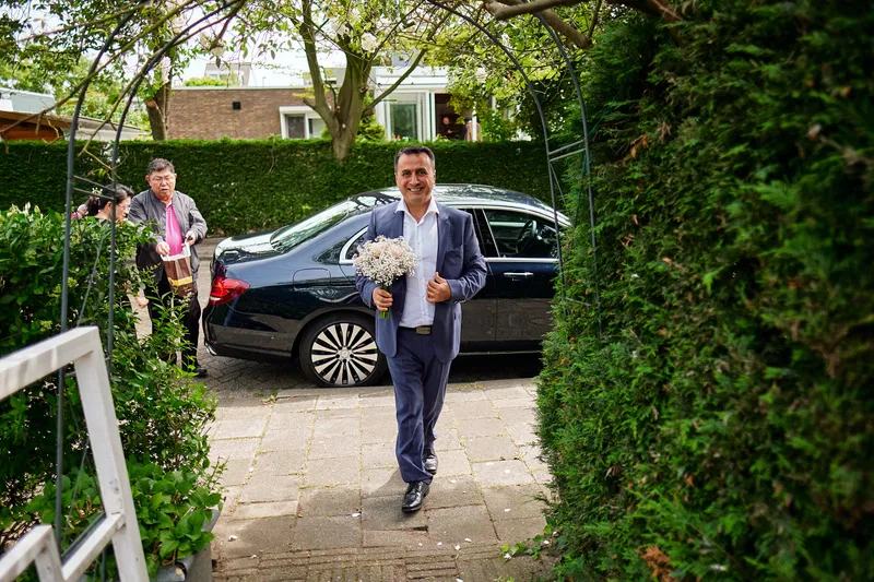 Eren loopt met het boeket over het tuinpad naar het huis