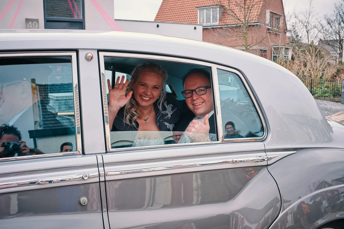 Maud en Sander zwaaien vanuit de witte Rolls-Royce