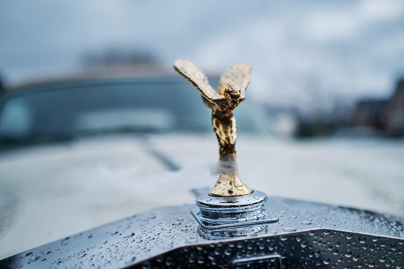 De Spirit of Ecstasy op de motorkap, met regendruppels