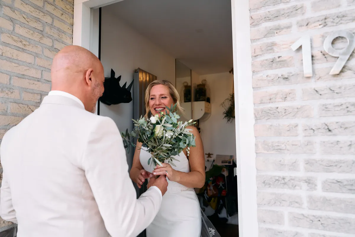 Danitsja en Brian zien elkaar in de deuropening, met het boeket tussen hen in
