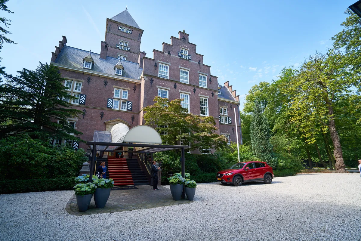 Kasteel Wittenburg in de zon, met de rode trouwauto op het grind