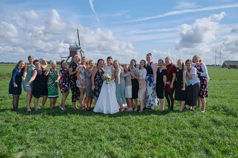Groepsfoto van alle gasten in de polder bij de molen