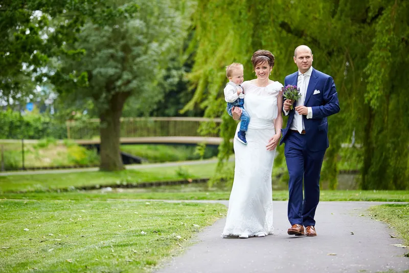 Marina en Erik lopen over het pad in het park, met hun zoontje op de arm