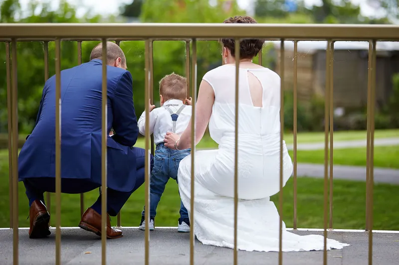 Marina en Erik hurken achter een hek, hun zoontje kijkt tussen de spijlen door