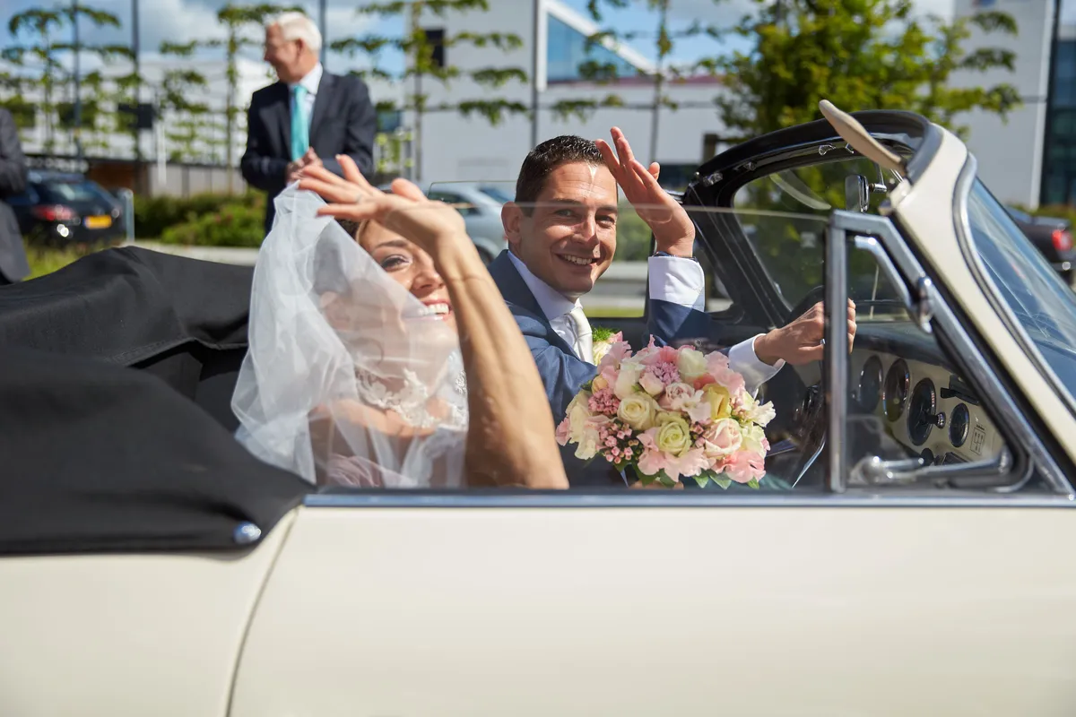 Sanne en Patrick zwaaien vanuit de witte Porsche