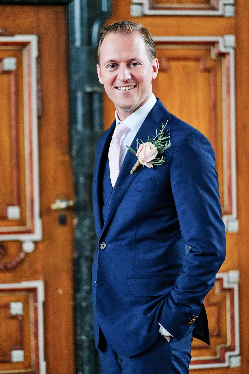 Mike in zijn blauwe pak voor de houten deur