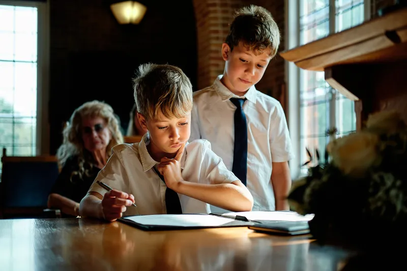 Een van de jongens tekent mee aan tafel