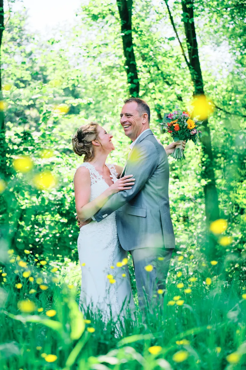 Raymond en Jilka lachen naar elkaar tussen het groen en de gele bloemen in het Westerpark