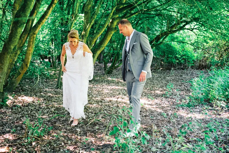Jilka en Raymond lopen door het bos in zacht licht onder de bomen