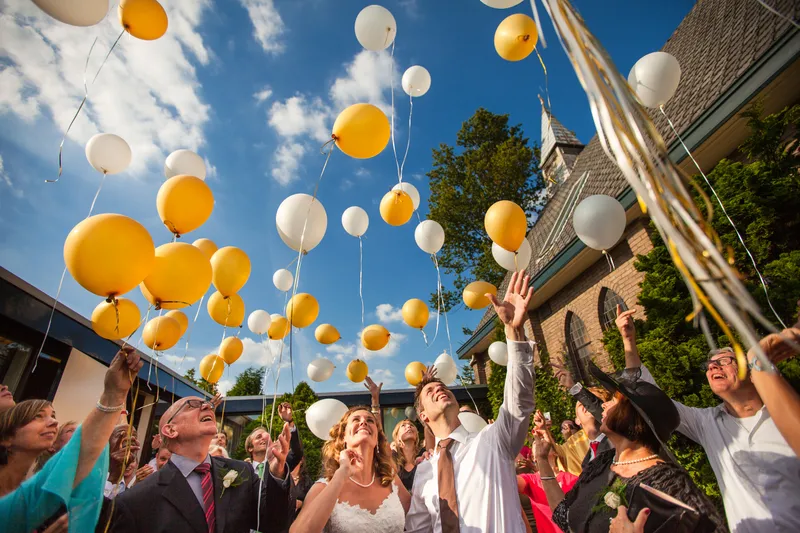 Gele en witte ballonnen gaan de lucht in naast de kerk