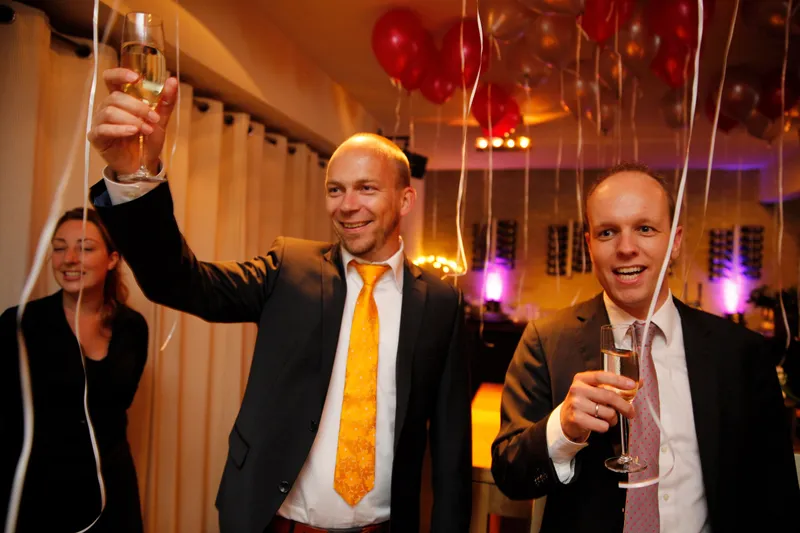 Een gast met gele das heft het glas