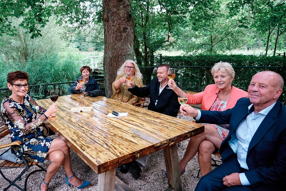Gasten aan de lange houten tafel in de tuin
