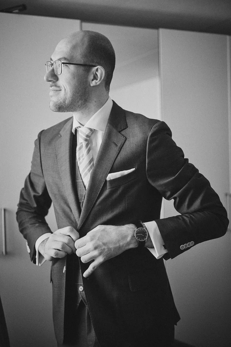Robbert trekt zijn colbert aan bij het raam