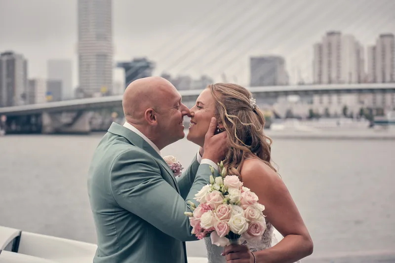 Kim en Dennis kussen elkaar aan het water, de brug op de achtergrond