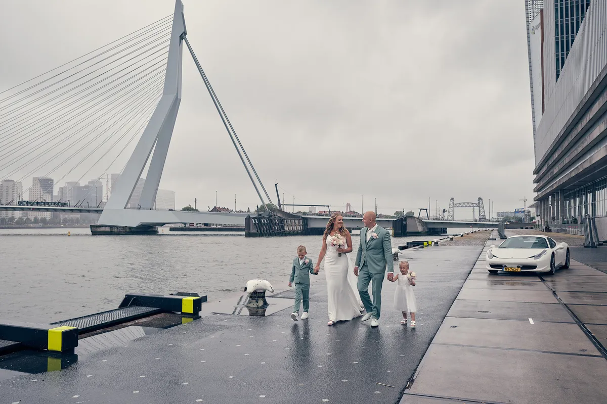Het gezin klein op de natte kade, met de Erasmusbrug en de Ferrari