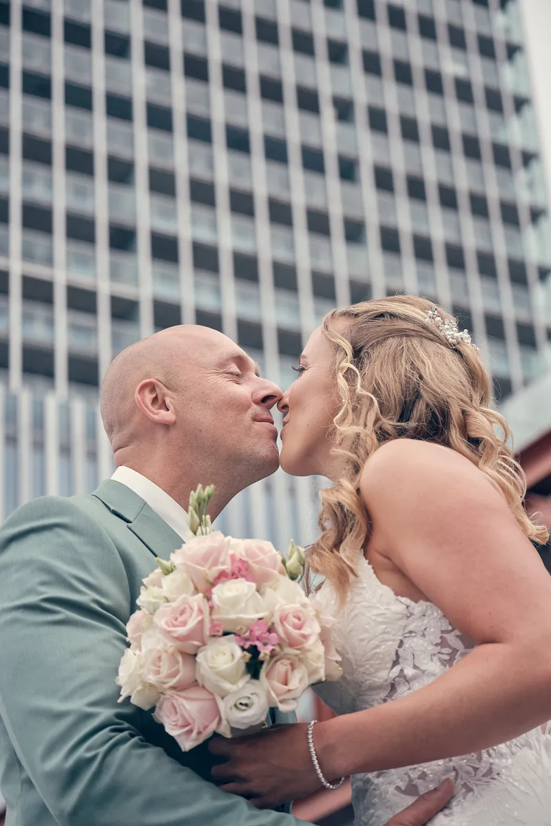 Kim en Dennis kussen elkaar voor een hoge glazen toren