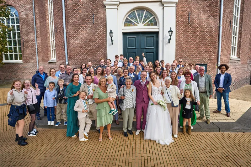 Groepsfoto met alle gasten voor de kerk