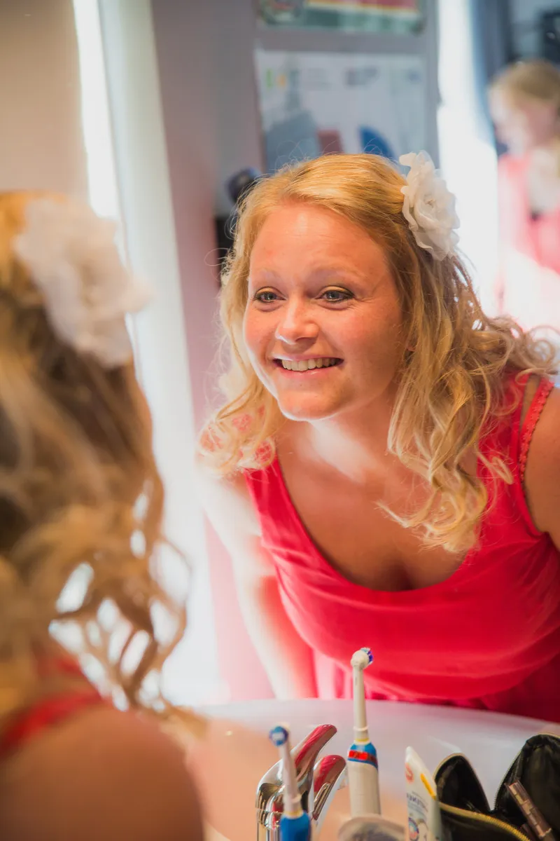 Sabine lacht in de spiegel terwijl haar haar wordt gedaan