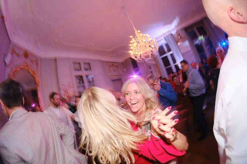 Sandra danst uitgelaten tussen de gasten onder een kroonluchter