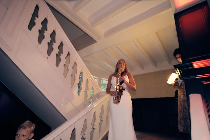 Kim speelt saxofoon bovenaan de witte trap