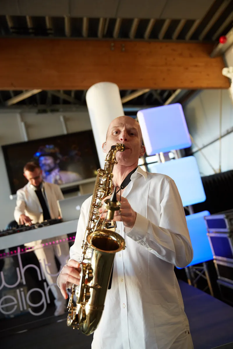 De saxofonist speelt naast de dj