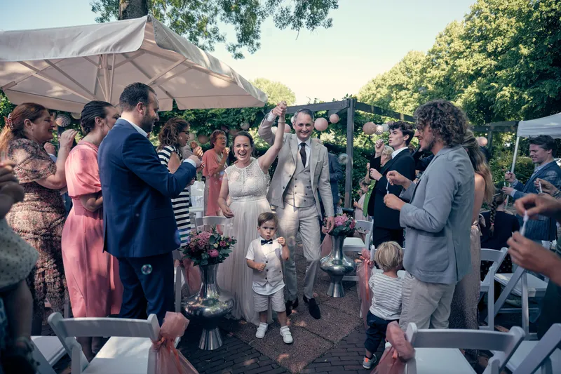 Evelien en Krijn lopen na de ceremonie tussen de juichende gasten door