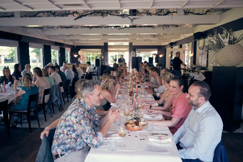 Lange gedekte tafels in de zaal van De Schaapskooi tijdens het diner