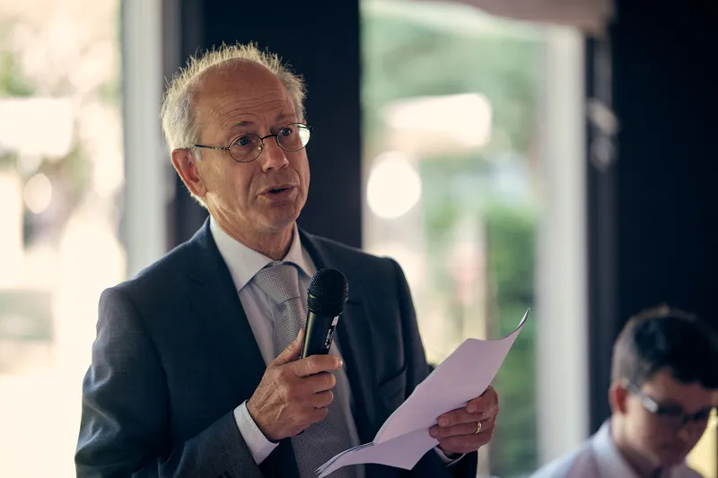 Een gast houdt met microfoon en briefje een speech tijdens het diner