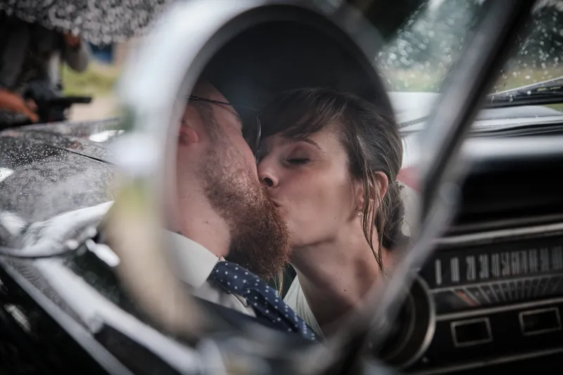 Barry en Milou kussen, gezien in de spiegel van de Mustang
