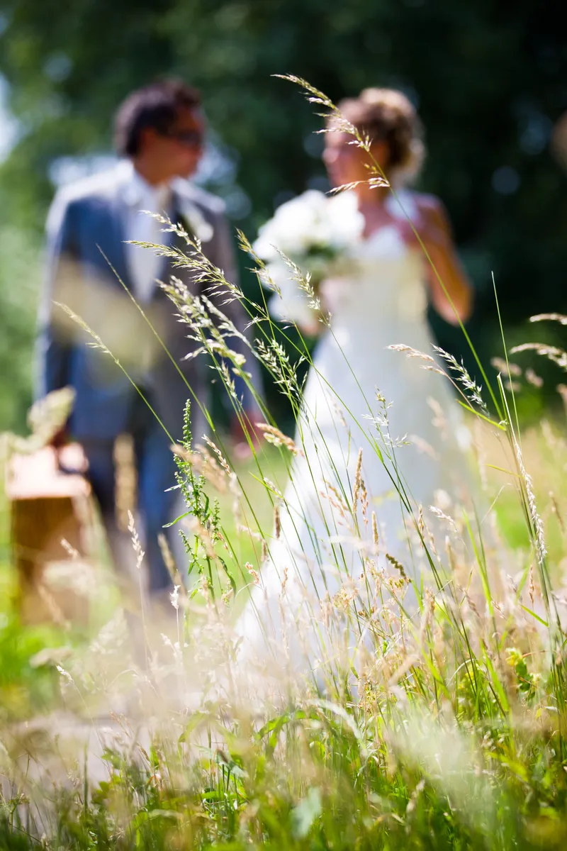 Rebecca met haar boeket in het hoge gras, Dennis erachter