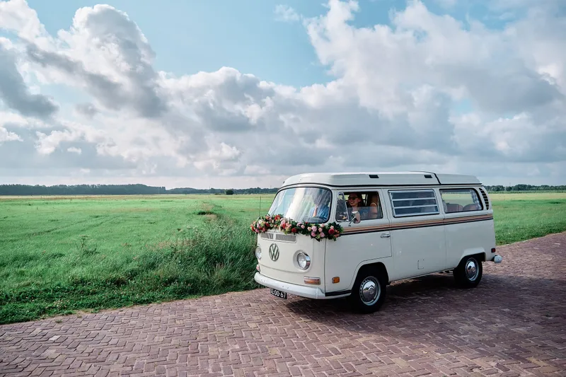 Het VW-busje op een weg door het weiland onder de wolken