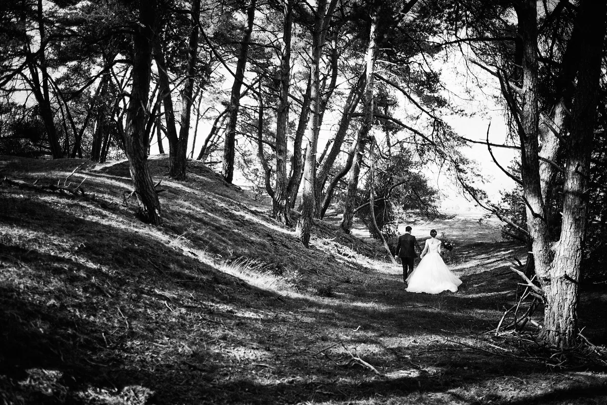 Kirsten en Jouke klein in het landschap van stuifzand en bomen, zwart-wit