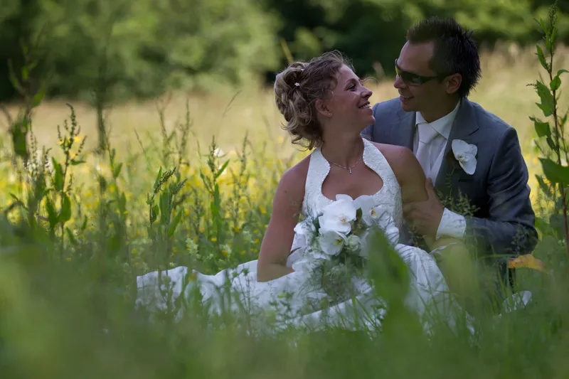 Dennis en Rebecca zitten lachend in het hoge gras